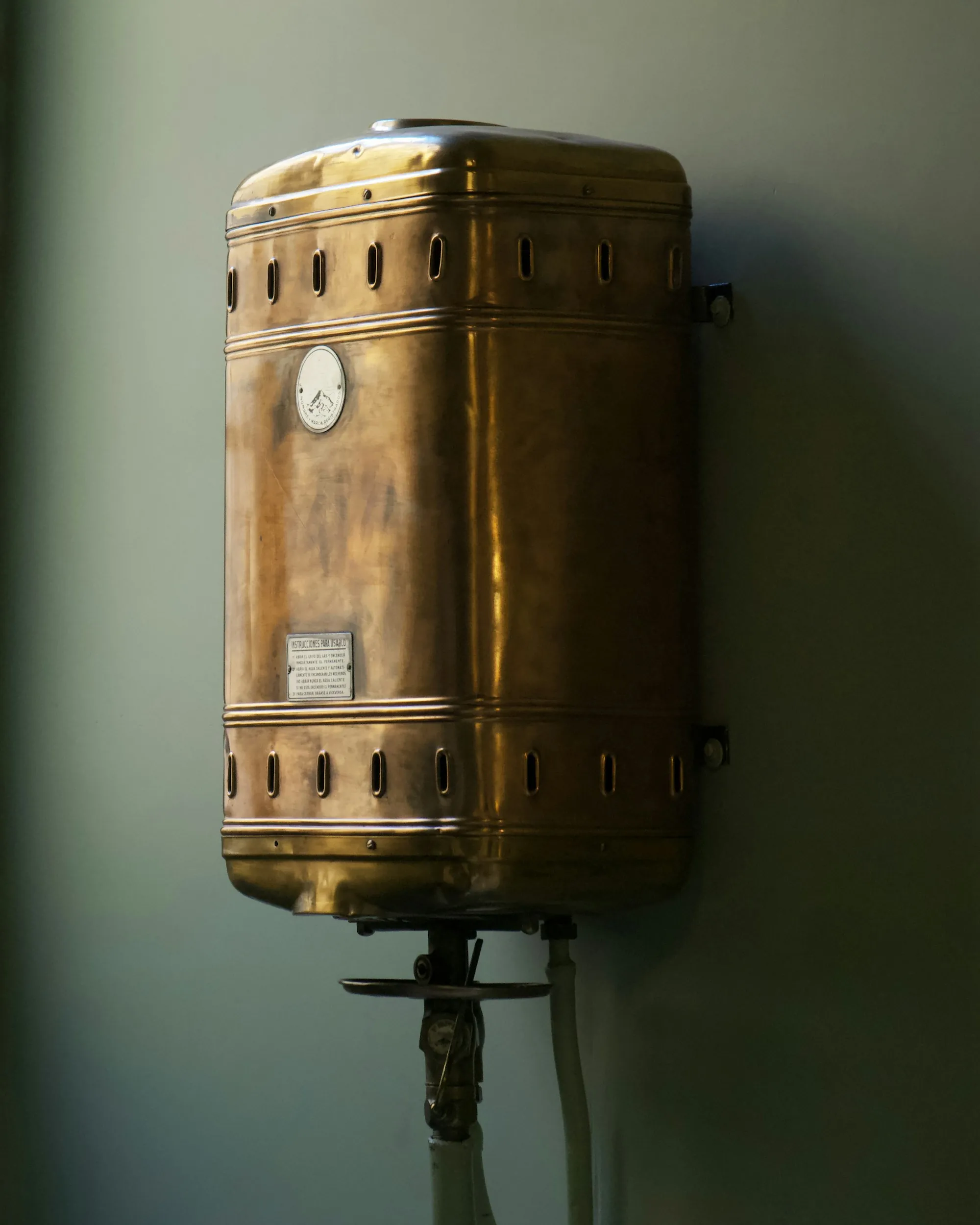 Copper water heater tank mounted on a green wall