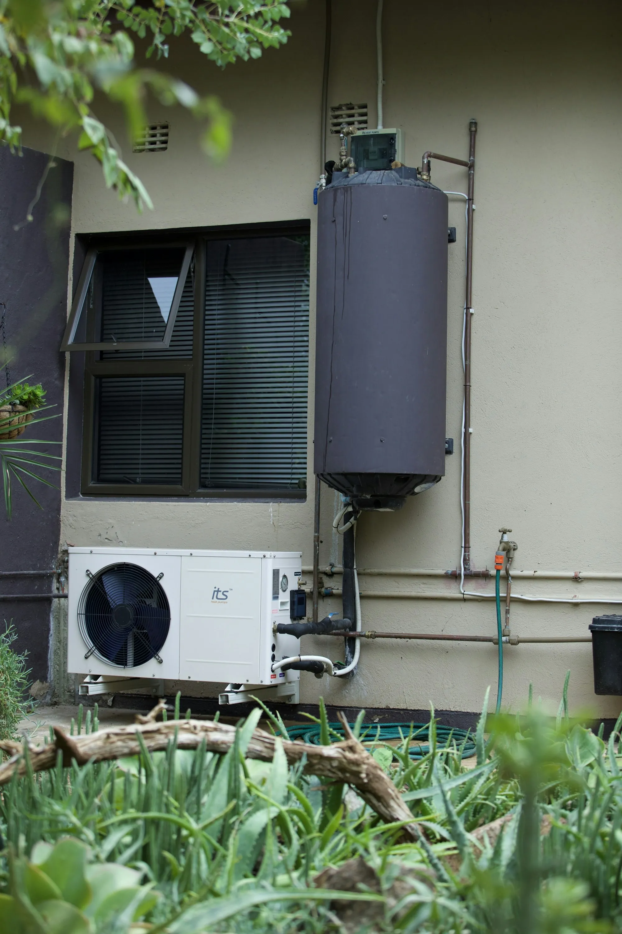 Heat pump unit and water heater on a home exterior wall